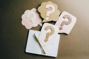 Carnet et bulles de question en papier découpé, symbolisant la démarche d’analyse dans un diagnostic organisationnel.