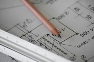 Plan de conception technique avec crayon posé, illustrant la préparation ergonomique en amont d’un projet