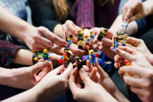 Mobilisation collective autour d’un projet, symbolisée par des mains tenant ensemble des figurines de travail