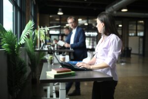 Salariée travaillant debout à un bureau réglable, illustrant l’aménagement ergonomique des postes de travail