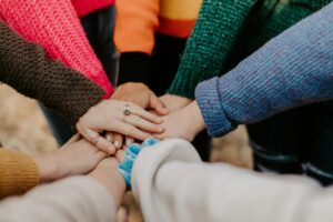 Mains posées les unes sur les autres en cercle, illustrant la force du collectif dans la prévention des RPS