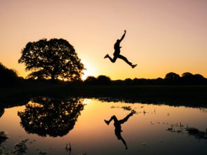 Silhouette en plein saut au coucher du soleil, illustrant le passage à l’action en prévention des RPS