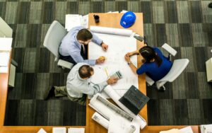 Équipe projet autour de plans d’aménagement, illustrant une conception d’espaces de travail intégrant les usages dès l’origine