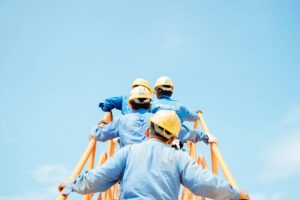 Groupe de salariés en tenue de chantier gravissant une structure, illustrant la transformation par la prévention des risques au travail