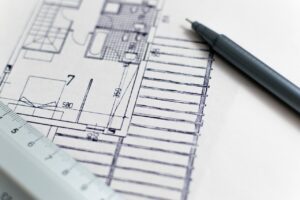 Plan architectural avec stylo et règle pour illustrer une démarche d’ergonomie de conception des espaces de travail