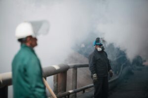 Travailleurs avec équipements de protection individuelle dans un environnement à risque, illustrant les liens entre QVCT et conditions de travail réelles