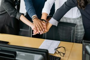 Mains réunies au-dessus d’une table de réunion illustrant la collaboration entre prévention RPS et management