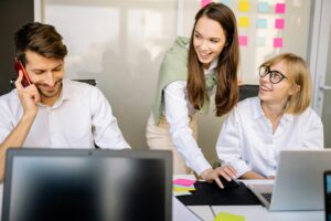 Trois collègues en train d’échanger avec le sourire autour d’un bureau, illustrant la co-construction du plan de formation CSE avec la direction