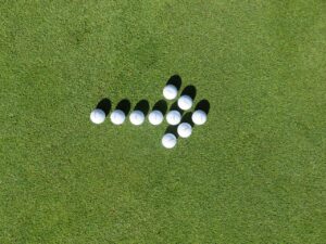 Flèche formée de balles de golf sur herbe illustrant la progression et le suivi d’une formation CSE dans le temps