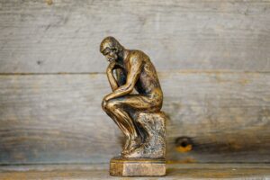 Statue du Penseur de Rodin sur fond en bois, symbolisant la réflexion des élus pendant leur formation CSE